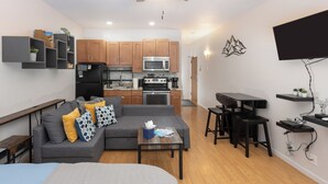 Een compact woongedeelte met een kitchenette, een slaapbank, een eethoek en een bed.