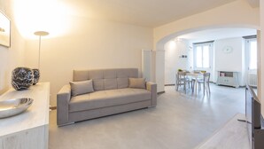 A modern living room with a sofa, a dining table, and a TV. - Nonna Sandrina in Monferrato hills, Garbagna, Italy (Garbagna)