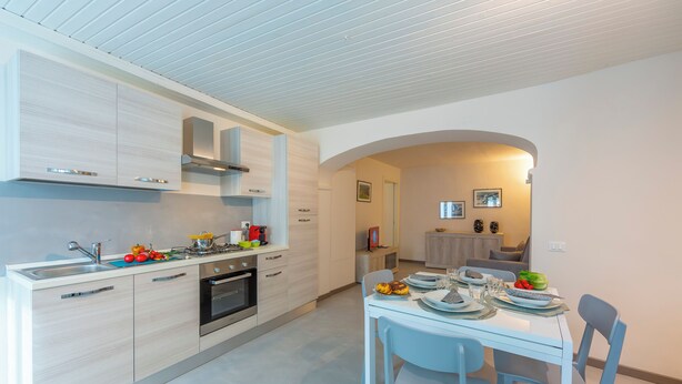 A modern kitchen with light wood cabinetry, a built-in oven, and a dining area with a white table and chairs. - Nonna Sandrina in Monferrato hills, Garbagna, Italy (Garbagna)