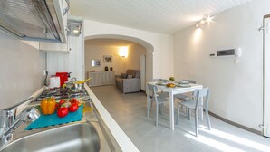 A modern kitchen with a stove, sink, and dining area with a table and chairs. - Nonna Sandrina in Monferrato hills, Garbagna, Italy (Garbagna)
