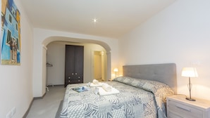 A hotel room with a large bed, a bedside table with a lamp, a wardrobe, and a painting on the wall. - Nonna Sandrina in Monferrato hills, Garbagna, Italy (Garbagna)