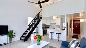 Een moderne woonkamer met een trap, een keuken en een eethoek.