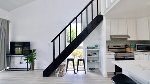 Een moderne keuken met witte kasten, een zwarte trap en een eethoek met een witte tafel.