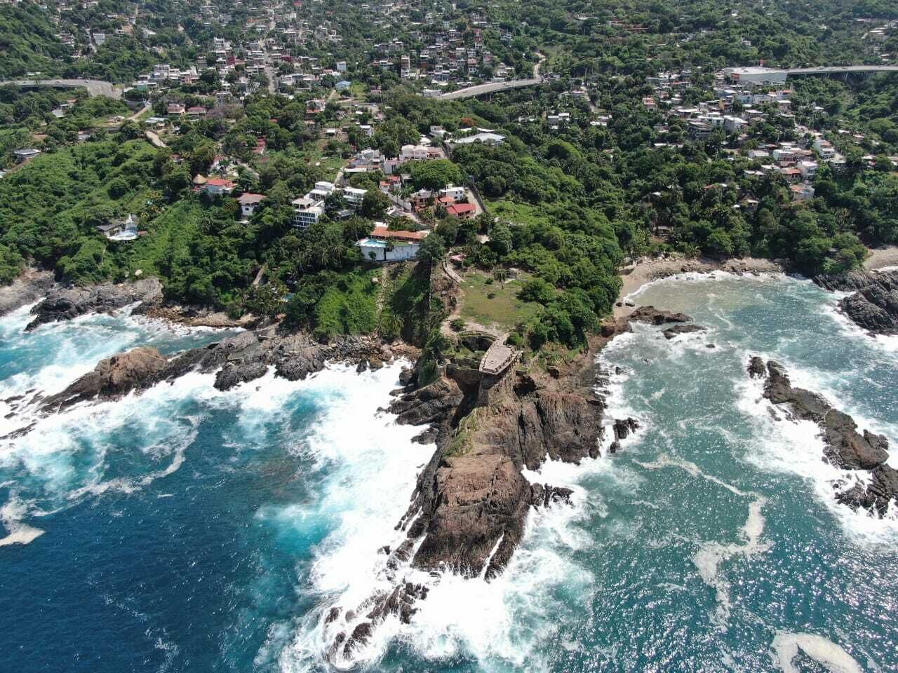 A coastal town with rocky cliffs, a bridge, and a beach.