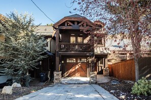 Une maison en bois à deux étages, dotée d’un garage, d’un balcon et d’une allée.