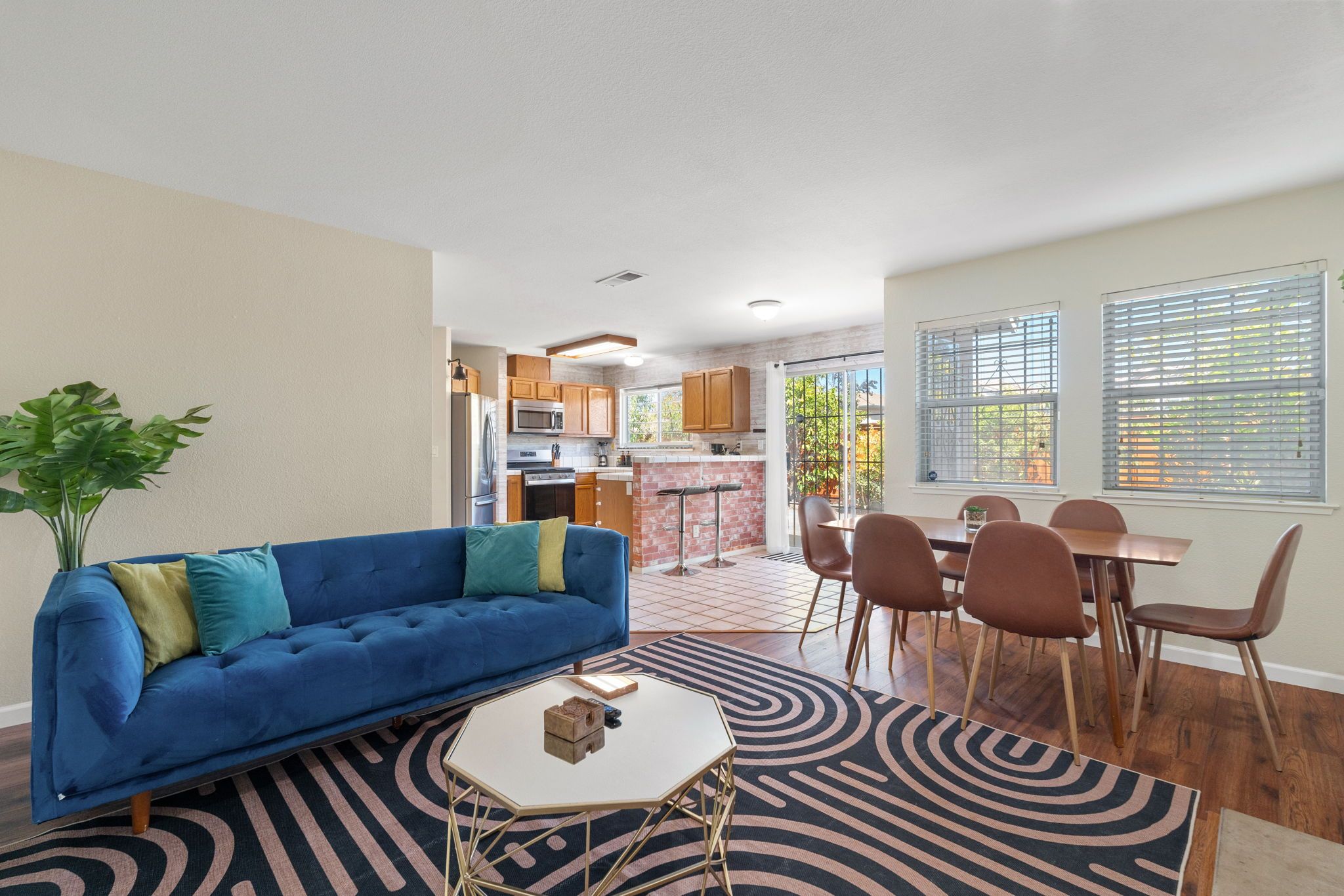 Ein modernes Wohnzimmer mit einem blauen Sofa, einem Couchtisch und einem Essbereich mit braunen Stühlen.