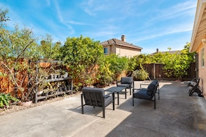 Eine Terrasse mit Gartenmöbeln, einem Holzzaun und verschiedenen Topfpflanzen.
