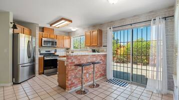 A modern kitchen with a refrigerator, stove, microwave, and a brick accent wall.