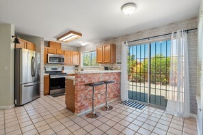 A modern kitchen with a refrigerator, stove, microwave, and a brick accent wall.