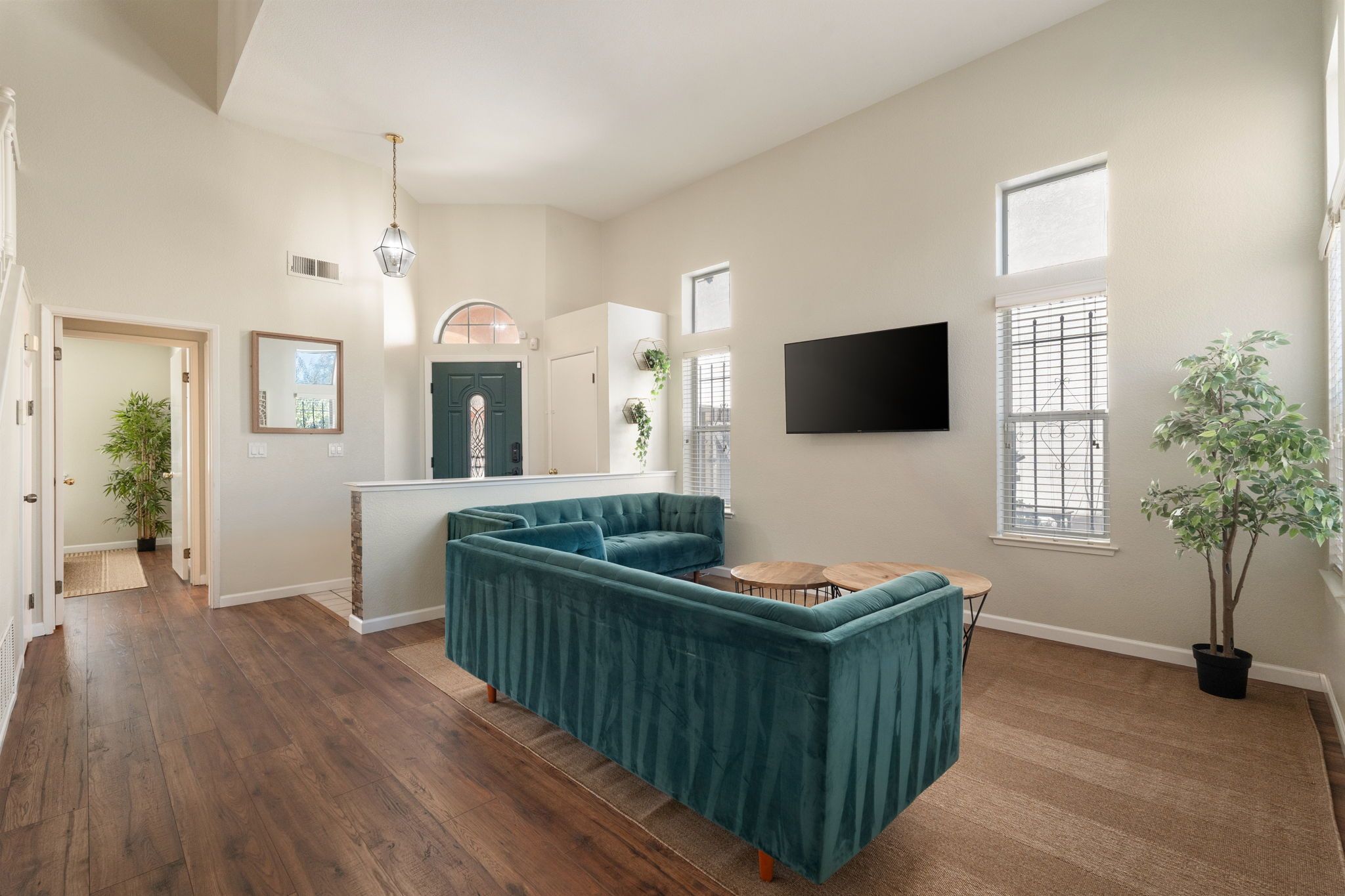 Una sala de estar amplia con un sofá modular, una mesa de comedor y un televisor de pantalla plana montado en la pared.