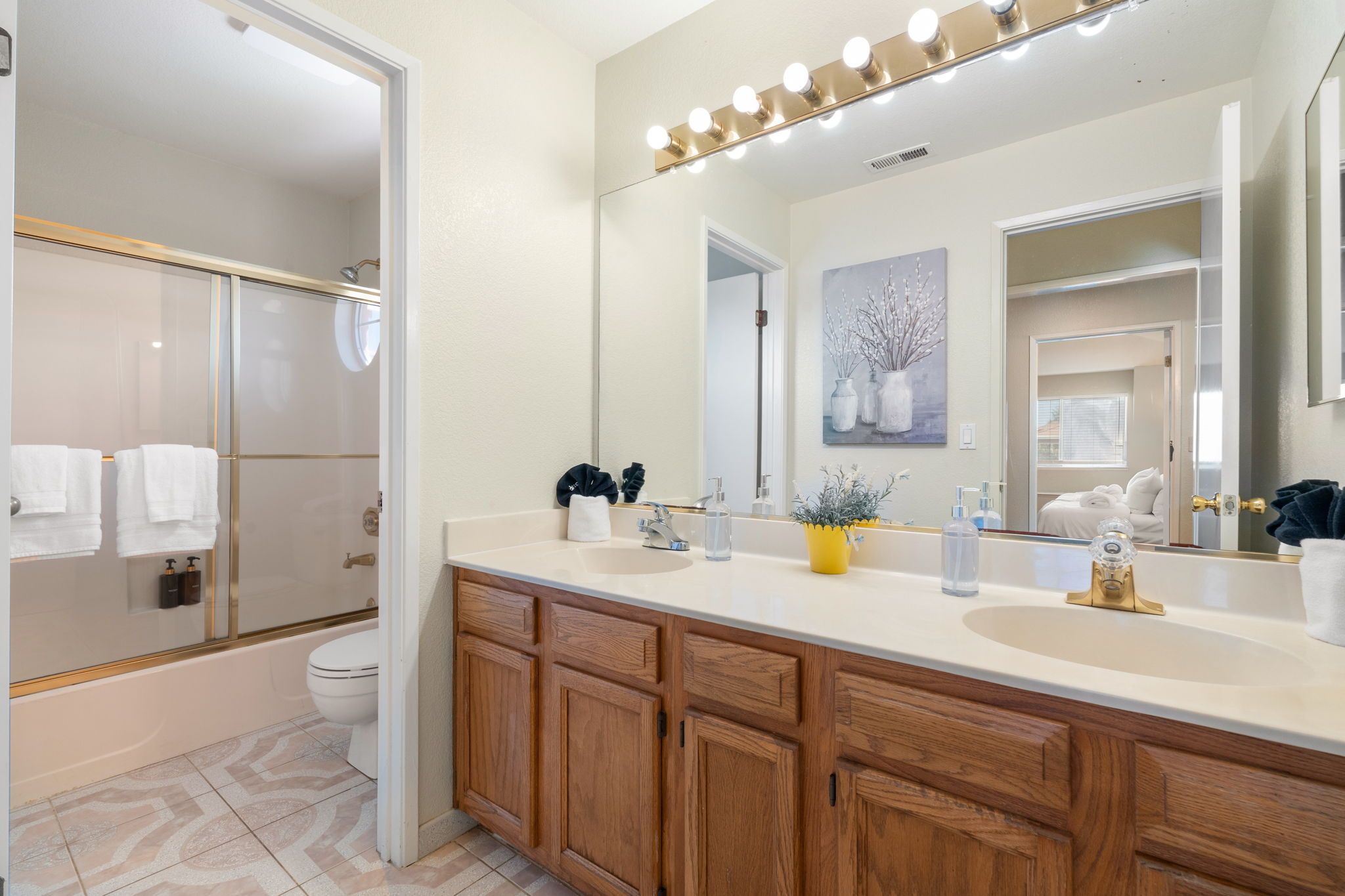 Un baño moderno con ducha a ras de suelo, un espejo grande y un tocador con grifo dorado.