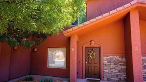 A building with a red exterior, a stone wall, a door with a wreath, and a window.