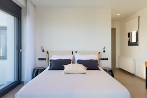 Une chambre d’hôtel moderne dotée d’un grand lit, de deux tables de chevet, d’une fenêtre offrant une vue agréable et d’un téléviseur fixé au mur.