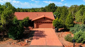 A house with a red-tiled roof, a garage, and a driveway leading to the entrance. - Experience luxury in Sedona Skies, a spacious 3-bedroom retreat in West Sedona. (Sedona)