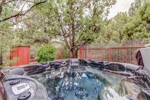 A hot tub surrounded by trees and a red fence. - Experience luxury in Sedona Skies, a spacious 3-bedroom retreat in West Sedona. (Sedona)