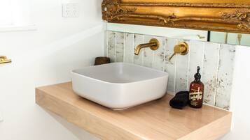 A bathroom with a white sink, gold faucets, and a mirror with an ornate gold frame.