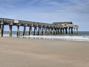 A pier extending into the ocean with a covered seating area and a sign indicating swimming restrictions. - Serene Getaway, Water Views, Heated Pool Access! (Tybee Island)