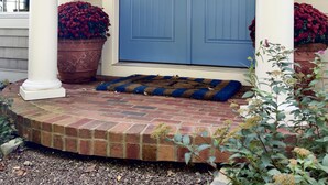 A blue front door with two wreaths, a brick porch, and two potted plants. - Beautiful Modern Cottage with Private Lake Access (Skaneateles)