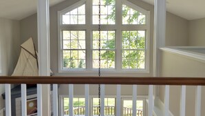 A spacious room with a high ceiling, large windows, and a view of a deck. - Beautiful Modern Cottage with Private Lake Access (Skaneateles)