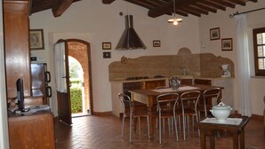 A kitchen with a wooden table, chairs, a stove, and a large overhead light.