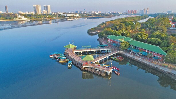 Un muelle a orillas del río con barcos, un embarcadero y un edificio con tejado verde.