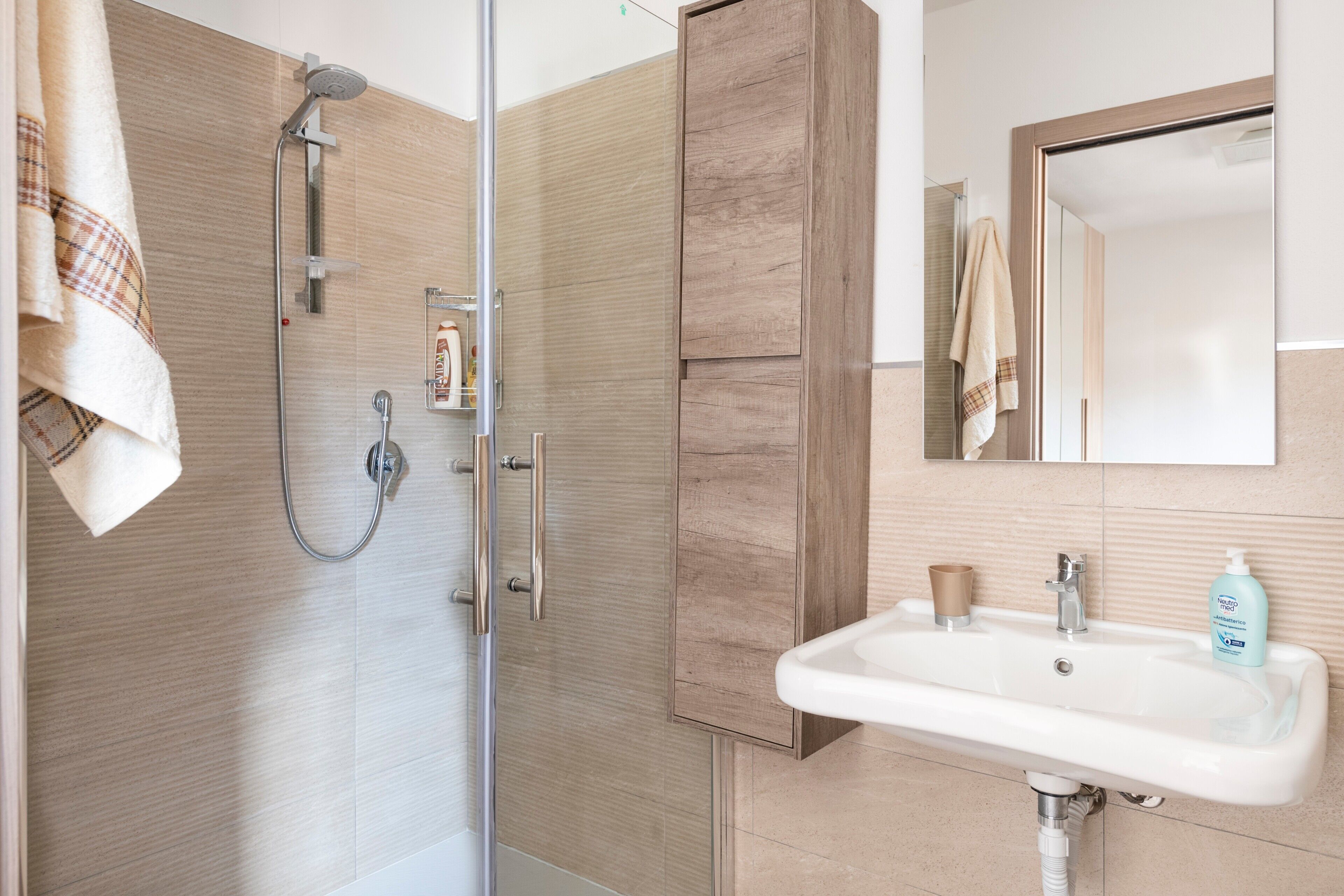 Un baño moderno con ducha, lavamanos y mueble de madera.