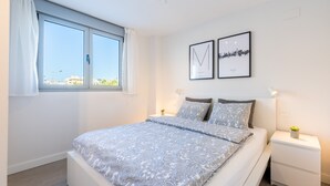 A bedroom with a large bed, a window with curtains, two framed pictures on the wall, and a bedside table with a lamp. - Apartment DunaBeach close to the Sea, with Pool & Balcony (Torrox Costa)