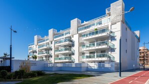 A modern multi-story hotel with balconies, a red bike lane, and a clear blue sky. - Apartment DunaBeach close to the Sea, with Pool & Balcony (Torrox Costa)