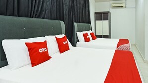 Una habitación de hotel con dos camas, cada una con ropa blanca y almohadas rojas.