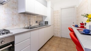 A modern kitchen with white cabinets, a microwave, a gas stove, and a sink.