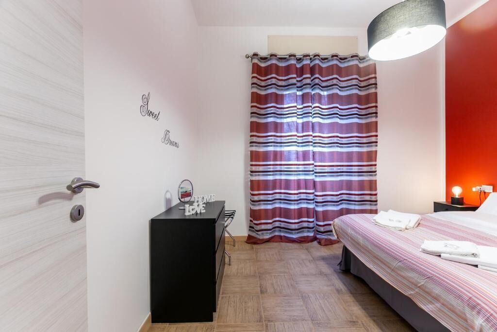 Une chambre à coucher avec un lit, un bureau, un miroir, une commode et un rideau à rayures.