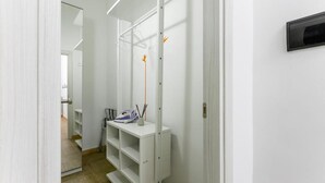 A narrow hallway with a white wardrobe, a mirror, and a shelf with a bag and pens.