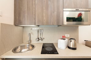 A modern kitchen with a stainless steel sink, a built-in toaster, a kettle, and wooden cabinets. - Saint Caterina House - Campo de' Fiori (Rome)