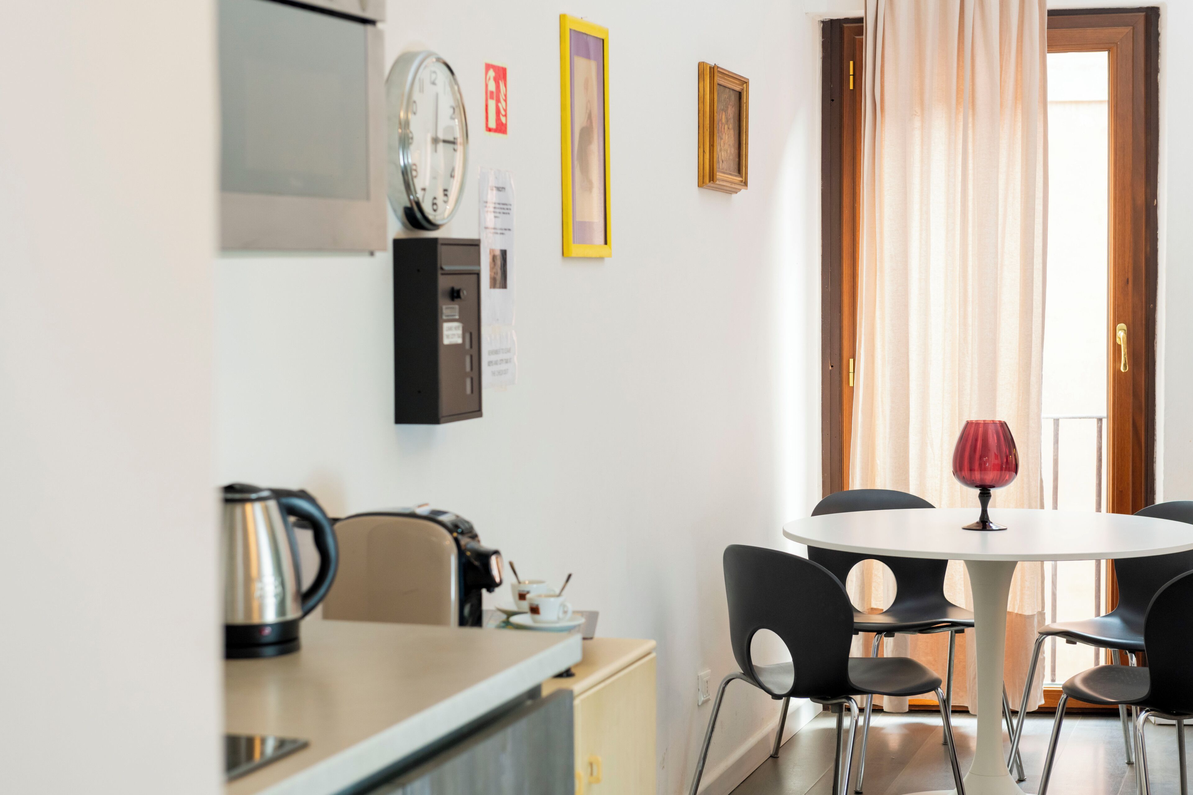 Una cocina con un hervidor, un reloj y un cuadro en la pared.