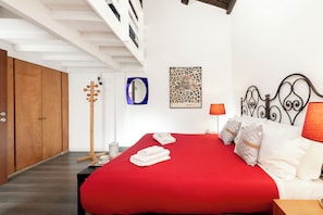 A bedroom with a red bedspread, wooden wardrobe, and a mirror on the wall. - Saint Caterina House - Campo de' Fiori (Rome)