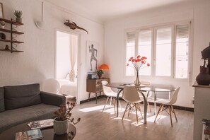 A modern living room with a sofa, a dining table with chairs, a coffee table with a plant, and a bookshelf. - Large charming apartment in the heart of Nîmes with spectacular rooftop, garage (Nîmes)