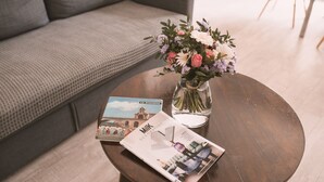 A round wooden table with a magazine and a vase of flowers. - Large charming apartment in the heart of Nîmes with spectacular rooftop, garage (Nîmes)