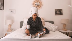 A person sitting on a bed in a room with a round mirror, two bedside tables with lamps, and framed pictures on the walls. - Large charming apartment in the heart of Nîmes with spectacular rooftop, garage (Nîmes)