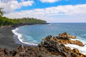 A coastal landscape with a rocky shoreline, a sandy beach, and a forested area. - 2Bed/1Bath Upstairs Home, 1mile to Beach, Next to State Forest, Custom Finishes (Pahoa)