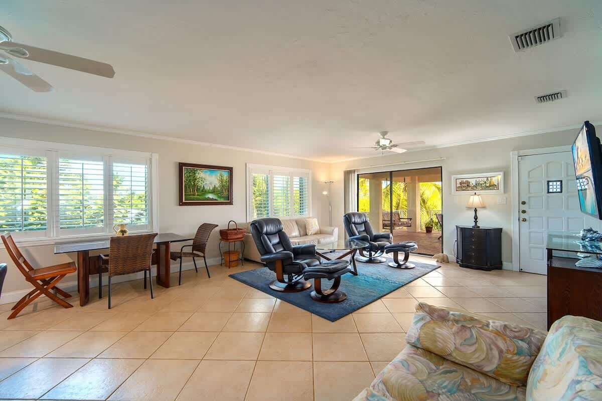 A spacious living room with a sofa, two recliners, a dining table with chairs, and a TV.