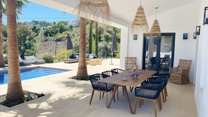 A modern outdoor dining area with a pool, lounge chairs, and a view of a hillside. - Finca Loma La Tapia (Cómpeta)