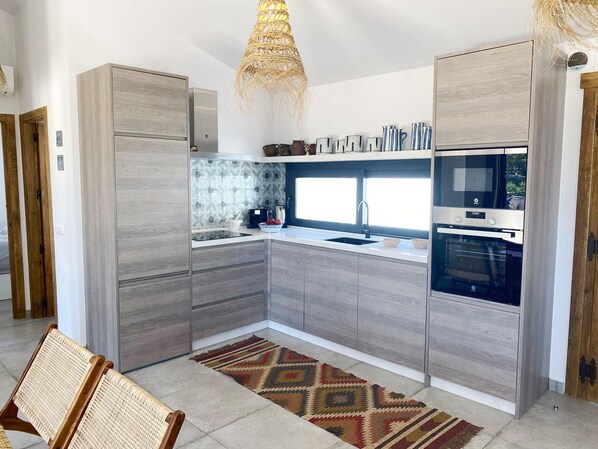 Una cucina moderna con mobili grigi, forno integrato e finestra sopra il lavello.