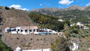 A hillside property with a pool, white buildings, and a mountainous backdrop. - Finca Loma La Tapia (Cómpeta)