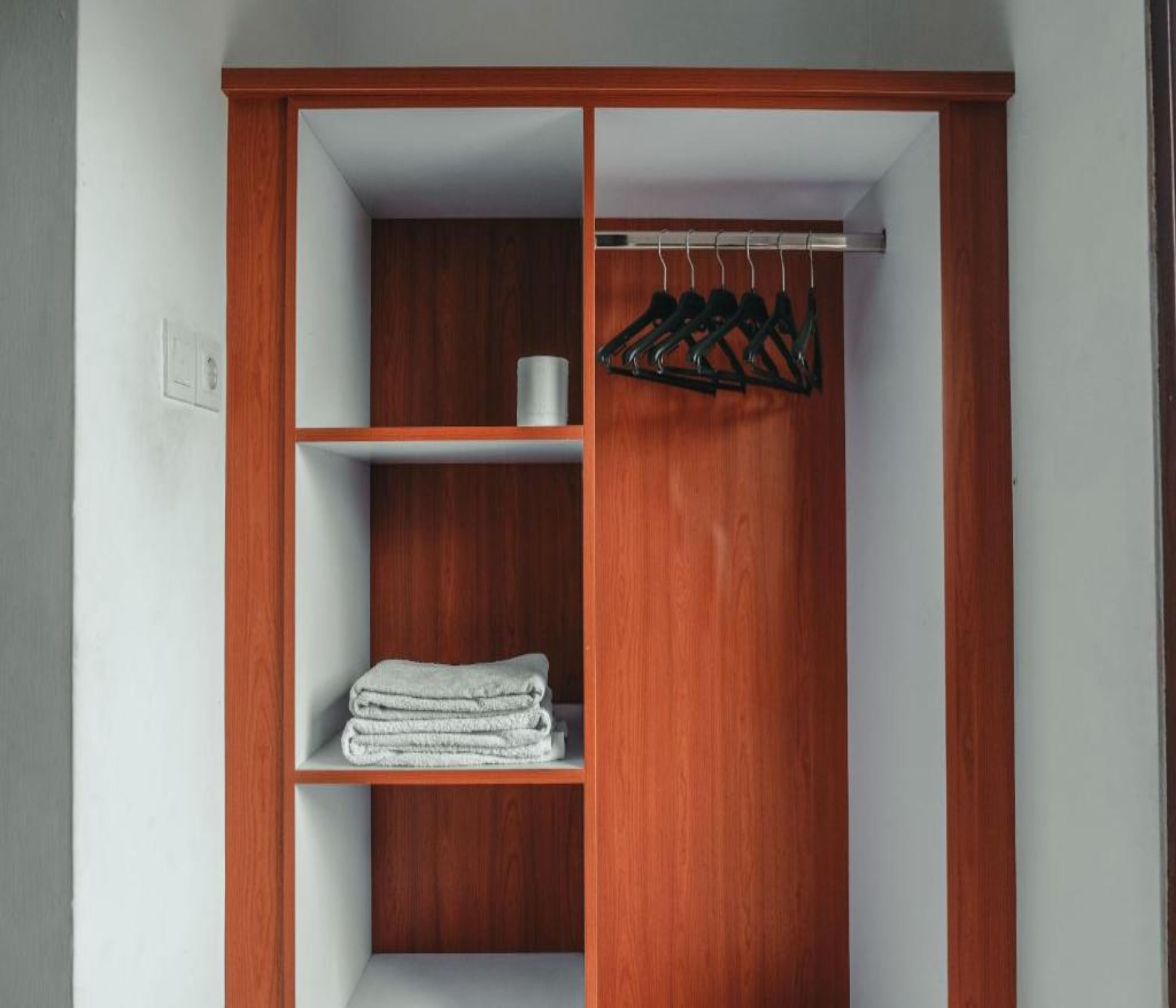 A wooden wardrobe with shelves and a hanging rod.