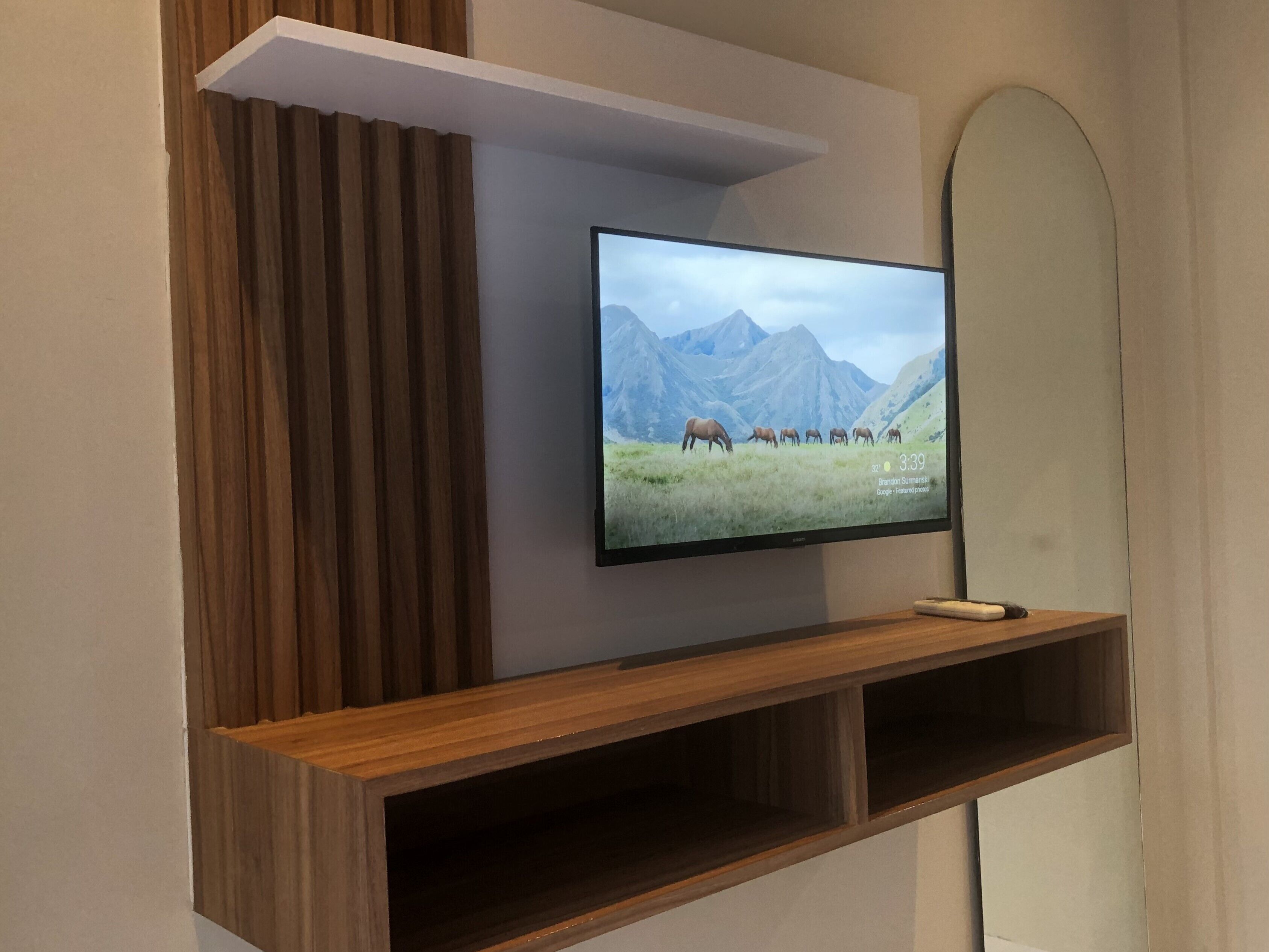 Un televisor de pantalla plana montado en un estante de madera con una imagen de un paisaje de montaña.