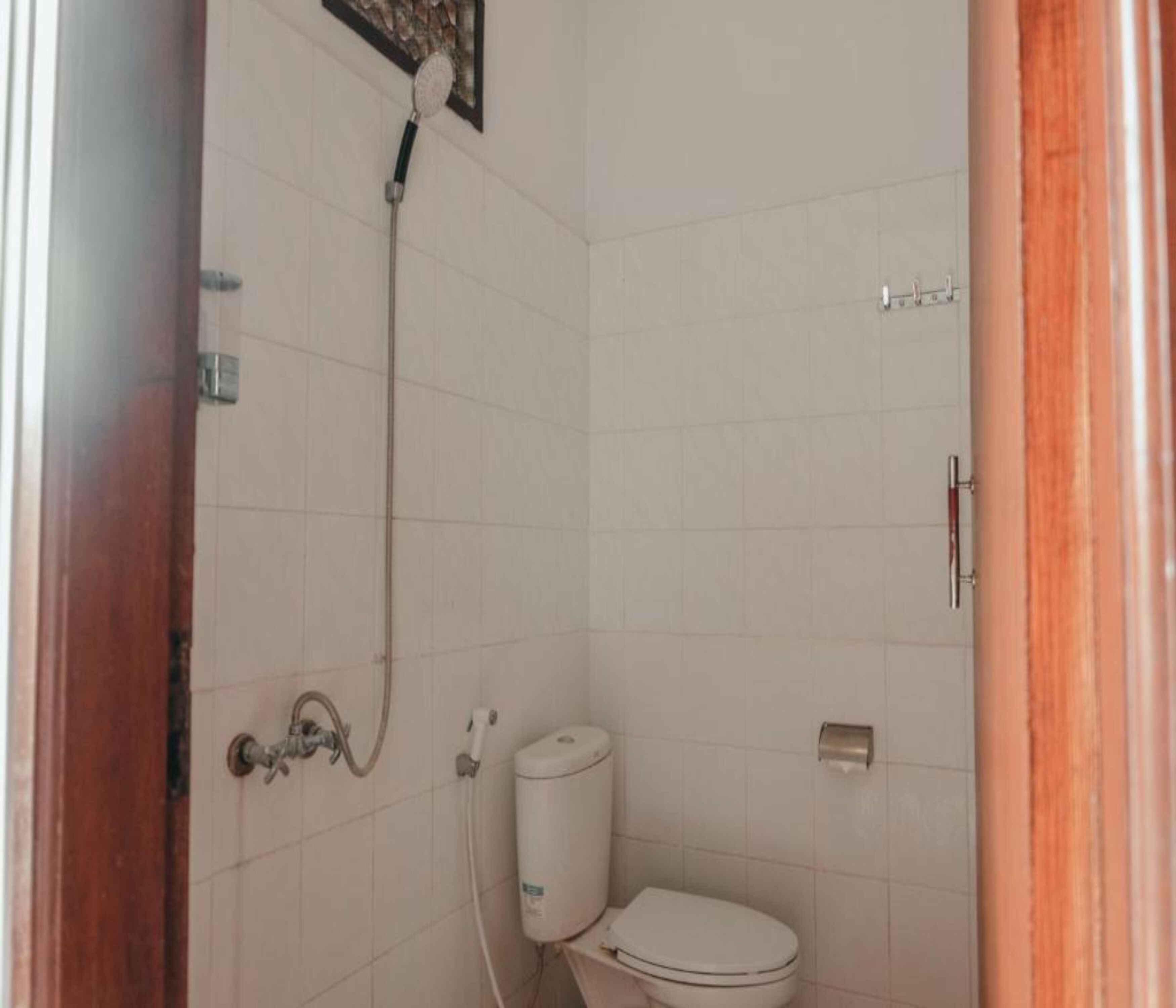 Une petite salle de bain compacte, équipée de toilettes, d’une douche et d’un porte-rouleau de papier toilette.