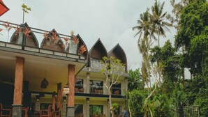 A hotel with a pool, multiple balconies, and tropical vegetation.