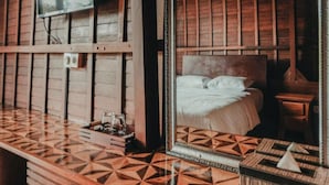 A room with a bed, a TV mounted on the wall, and a patterned floor.
