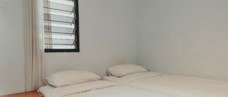 A simple, clean room with a bed, a nightstand, and a window with blinds.