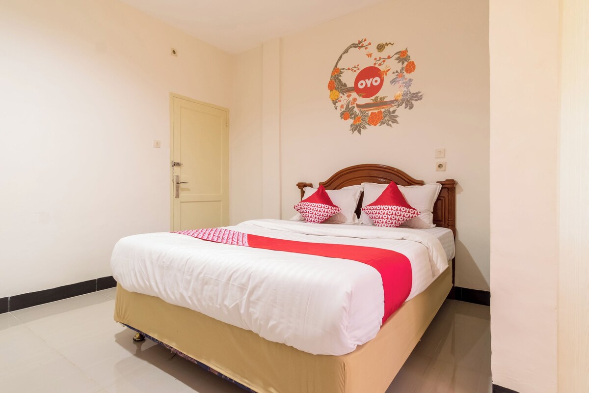 Quarto de hotel com uma cama, uma porta e um ornamento na parede.